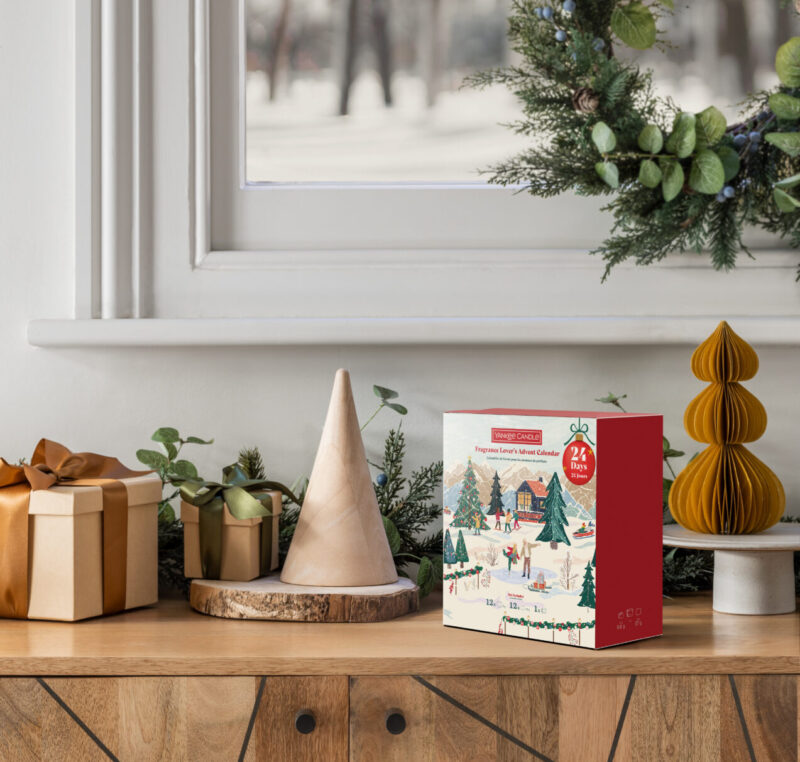 Juldekoration med adventskalender och gåvor på träbord, vinterlandskap i bakgrunden.