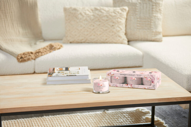 Yankee Candle på träbord i mysigt vardagsrum.